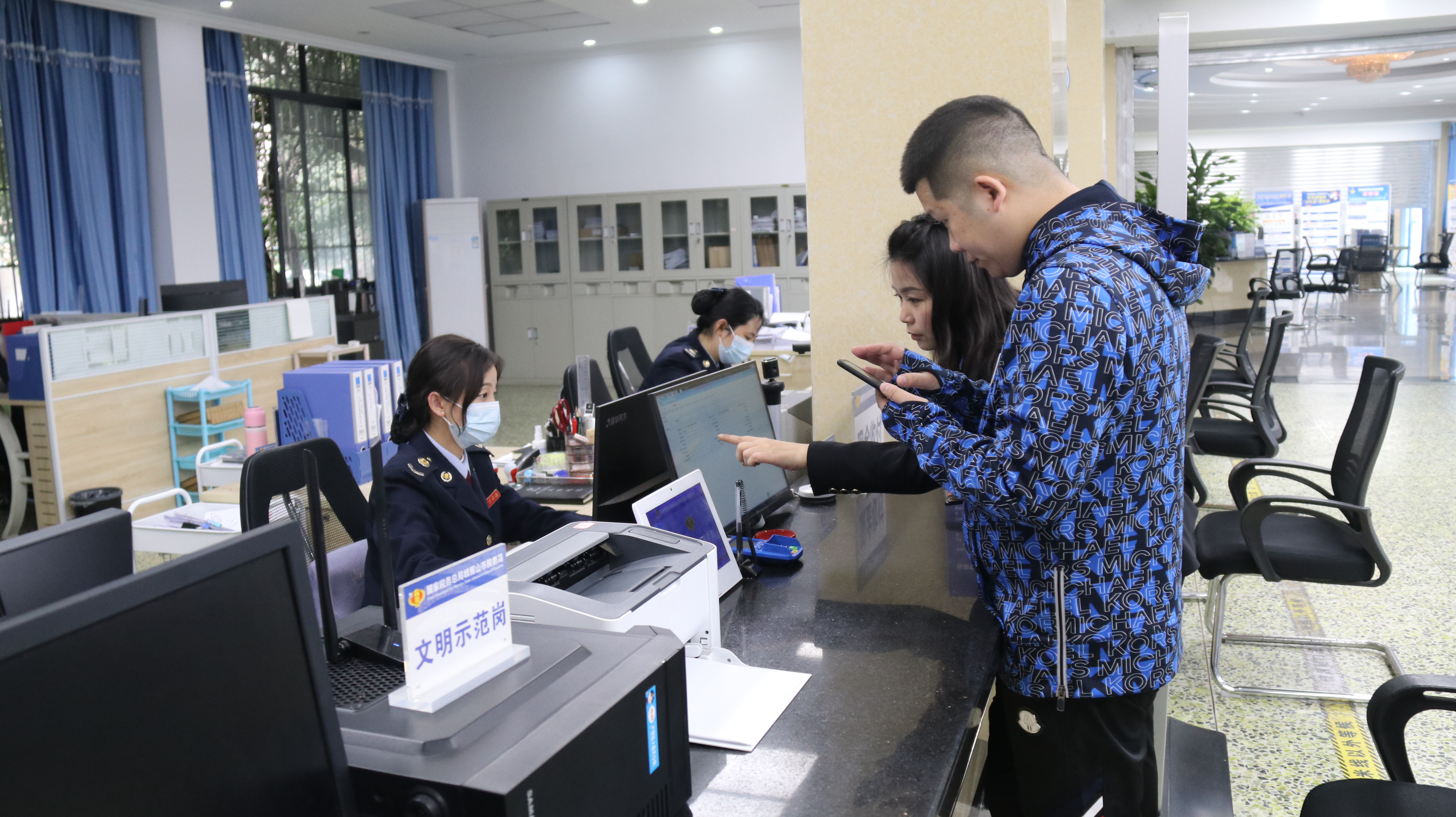 峨眉山市税务局办税服务厅工作人员为纳税人办理业务