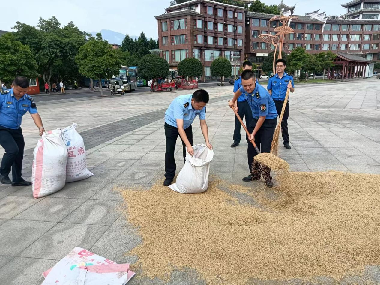 帮助群众收起晾晒在广场的稻谷
